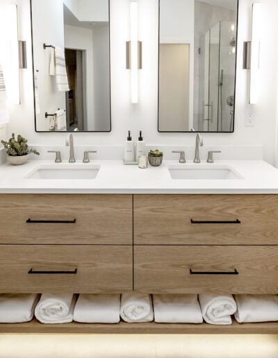 A bathroom with a wooden vanity and white towels.