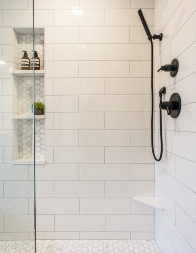 A white tiled shower with a glass shower door.