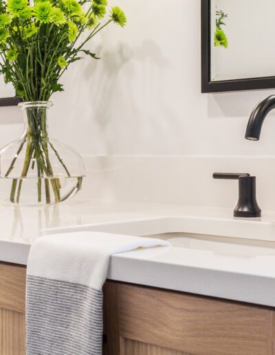 A white bathroom with black faucets and mirrors.