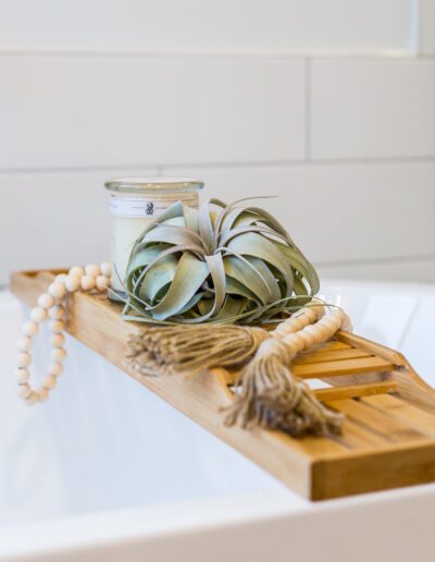 A wooden tray with a candle and a plant on it.