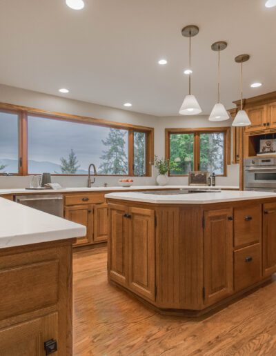 Modern kitchen with wooden cabinets, central island, stainless steel appliances, and large windows with a view.