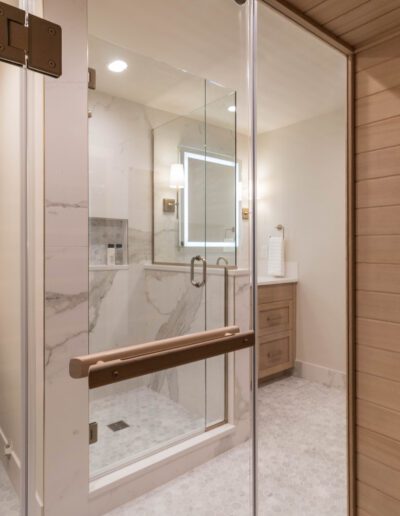 Modern bathroom featuring a glass shower stall, white toilet, wooden cabinets, and a towel heater on a wooden wall.